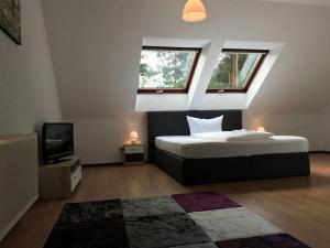 a bedroom with a bed and a tv and two windows at Lokal Genial Pension & Restaurant in Beelitz