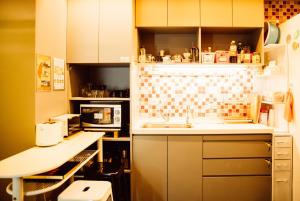 a kitchen with a stove, sink, and refrigerator at On My Way - Taipei Hostel in Taipei