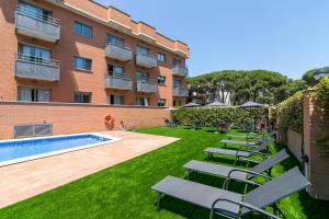 a courtyard with lounge chairs and a swimming pool at Aparthotel Bardon in Castelldefels