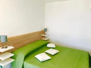 una camera con un letto verde con due cuscini di Il Caprarizzo a Palinuro