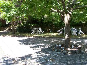 eine Gruppe von Tischen und Stühlen unter einem Baum in der Unterkunft Le Cévenn'hols in Le Vigan