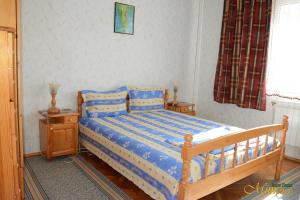 1 dormitorio con cama de madera con sábanas azules y blancas en Guest House Mimosa, en Balchik
