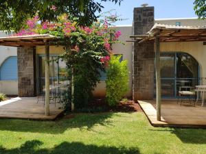 a deck with a pergola with pink flowers on it at Nano's Place in Ma‘yan Barukh