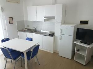 a kitchen with a white table and a white refrigerator at Hotel Residence Adriana in Cesenatico