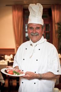 un homme dans un chapeau de chef tenant une assiette de nourriture dans l'établissement St. David's Hotels Paddington, à Londres