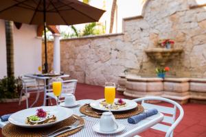 a table with plates of food and two glasses of orange juice at Chez Waffle Hotel in Puerto Aventuras