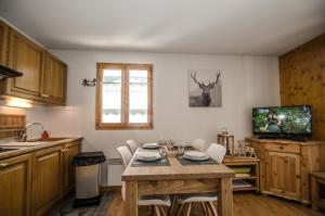 uma cozinha com uma mesa com cadeiras e uma televisão em Litchi Apartment em Chamonix-Mont-Blanc