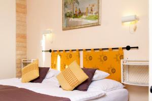 ein Schlafzimmer mit einem Bett mit einem gelben Kopfteil in der Unterkunft Albergo Giardino in Balatongyörök