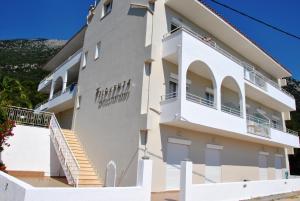 a large white building with stairs in front of it at Filoxenia Hotel & Apartments in Póros Kefalonias