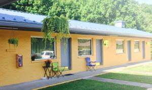 a yellow house with chairs sitting outside of it at Greystone Motel in Hillsboro