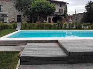 una piscina con terrazza in legno accanto a una casa di Agriturismo Borgo Floreani a Vendoglio