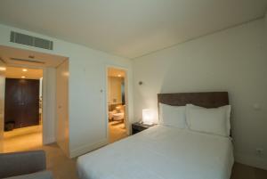 a bedroom with a white bed and a living room at Troia Residence by The Editory - Apartamentos Marina in Troia