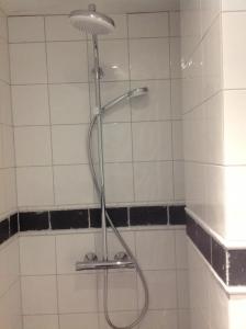 a shower with a hose in a white tiled bathroom at B&B van Beijden in Overasselt