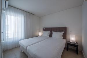 a bedroom with a large white bed with two lamps at Troia Residence by The Editory - Apartamentos Marina in Troia