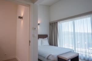 a bedroom with a bed and a large window at Troia Residence by The Editory - Apartamentos Marina in Troia