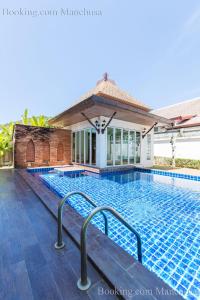 a swimming pool at a villa with a house at BaanManchusa Thai Villa in Rawai Beach