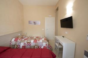 a bedroom with a bed and a desk and a television at Vela Latina Affittacamere in Marsala