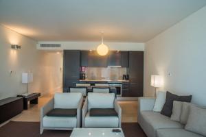 a living room with a couch and chairs and a kitchen at Troia Residence by The Editory - Apartamentos Marina in Troia