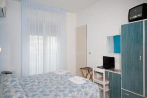 a bedroom with a bed and a desk with a computer at Hotel Marilinda in Cesenatico