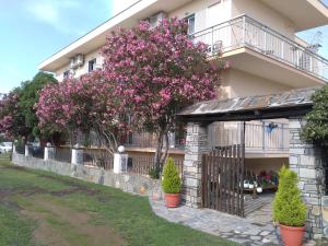 a building with a gate and trees with pink flowers at Patra Rooms Skala Prinou in Prinos