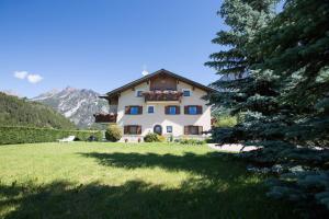 a large house in a field with a tree at Casa Margherita in Bormio