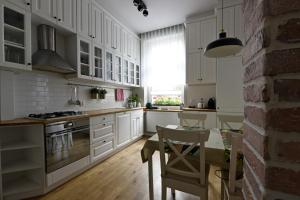 a kitchen with white cabinets and a table and chairs at Like at Home in Sopot