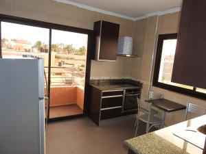 a kitchen with a refrigerator and a table and a window at Résidence Vladimiro Ariano in Laayoune
