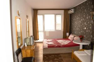 a bedroom with a bed and a table and a window at Hotel Romantic in Byala +23 photos