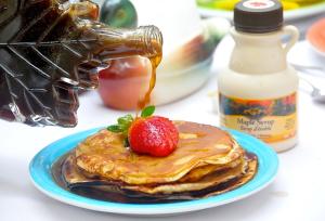 a white plate topped with pancakes and strawberries at Canada Lodge Campos do Jordão in Campos do Jordão