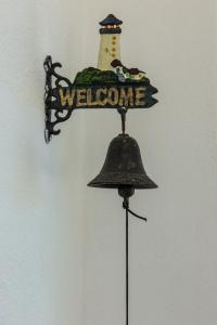 a welcome sign with a lighthouse on top of a bell at Villa il Poderino in Marina di Campo