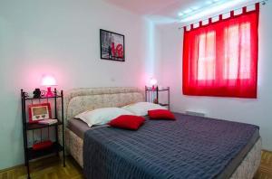a bedroom with a bed with two pillows and a red window at Dani in Trogir