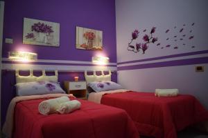 1 dormitorio con 2 camas con sábanas rojas y paredes moradas en I Petali Guest House en Roma