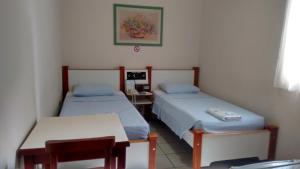 a room with two beds and a table and a desk at Podium Hotel in São Caetano do Sul