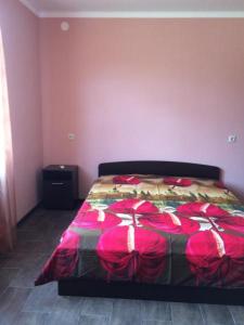 1 dormitorio con 1 cama grande con sábanas rojas en Гостевой дом ESHERA, en Sukhum