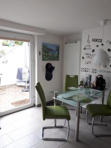 a dining room with a glass table and green chairs at Bella Casa & Belle Maison in Saarbrücken