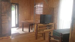 een woonkamer met een tv en een tafel met een stoel bij A Cantina Chalet avec Piscine proche d Ajaccio in Carbuccia