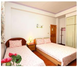 2 camas en una habitación con 2 flores rosas en Yilan Xiang Feng Homestay, en Wujie