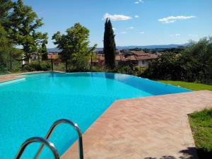 a swimming pool with blue water in a yard at Appartamenti Villa Abbraccio in Siena