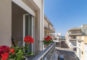 a balcony with red flowers on a building at Incentro in Gallipoli