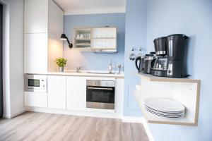 a kitchen with white cabinets and a coffee maker at Hafenapartments Warnemünde in Warnemünde