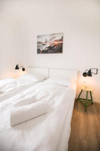 a white bed with white sheets and pillows at Hafenapartments Warnemünde in Warnemünde
