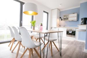 a kitchen and dining room with a table and white chairs at Hafenapartments Warnemünde in Warnemünde