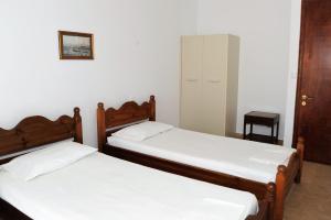 two beds in a small room with white walls at Captains Studios & Apartments in Kavos