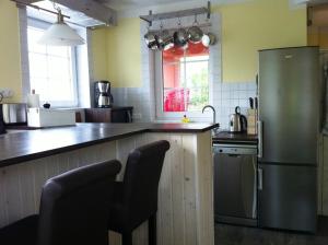 a kitchen with a refrigerator and a counter with chairs at Haus Hafenecke in Freest