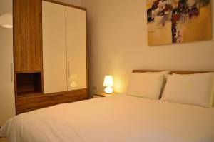 a bedroom with a white bed and a cabinet at Hepburn Holiday Apartment in Birżebbuġa