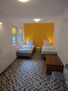 2 Betten in einem Zimmer mit gelber Wand in der Unterkunft Wein und Stein in Randersacker