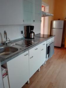 a kitchen with white cabinets and a sink and a refrigerator at Gästezimmer Fuchs in Neuhausen auf den Fildern