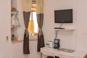 a room with a table and a television and a window at Apartment and room Sveti Jakov in Dubrovnik