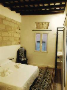 een slaapkamer met een wit bed en een raam bij Le Case Del Grillo in Trapani