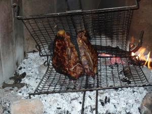 two pieces of meat are cooking on a grill at La Sassetta in Bibbona